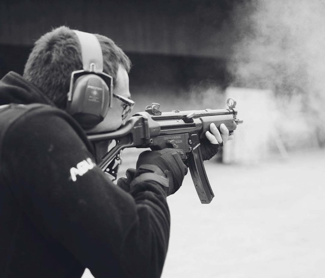 Trainee firing a submachine gun on the outdoor range, smoke leaving the muzzle