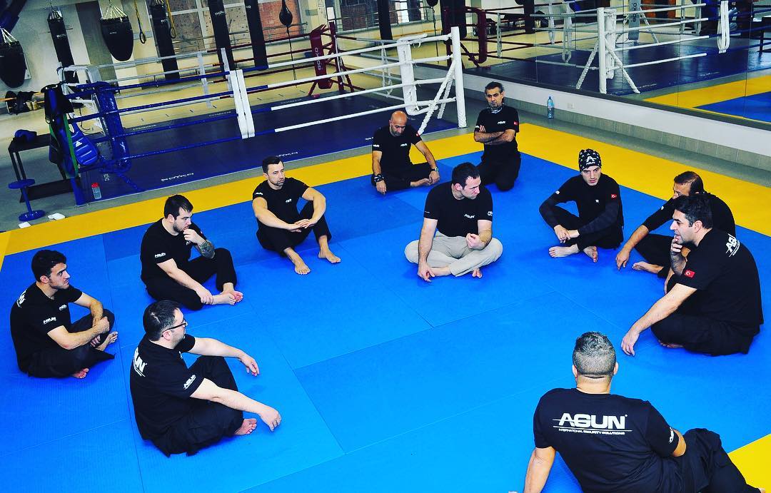 Team seated in a circle on the mat for a briefing