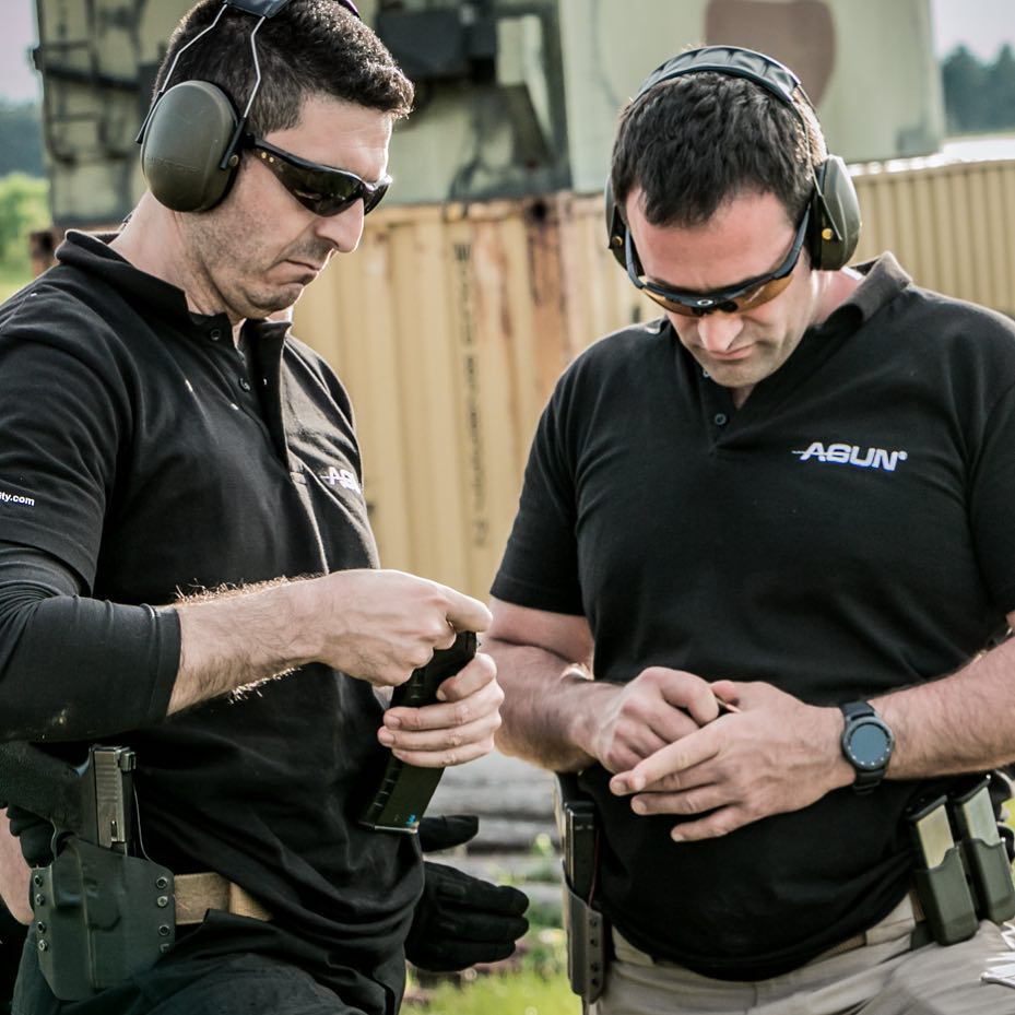 Two instructors checking pistol magazines beside the range containers