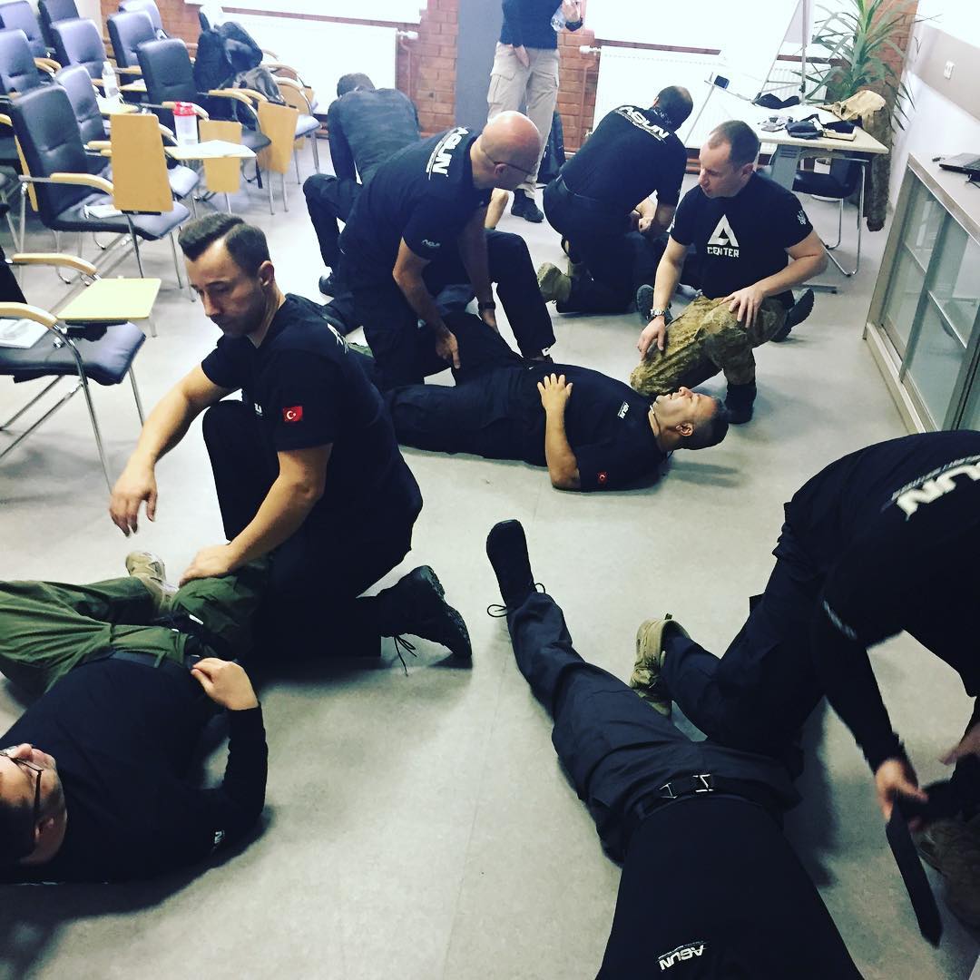 Pairs practising restraint techniques on a classroom floor