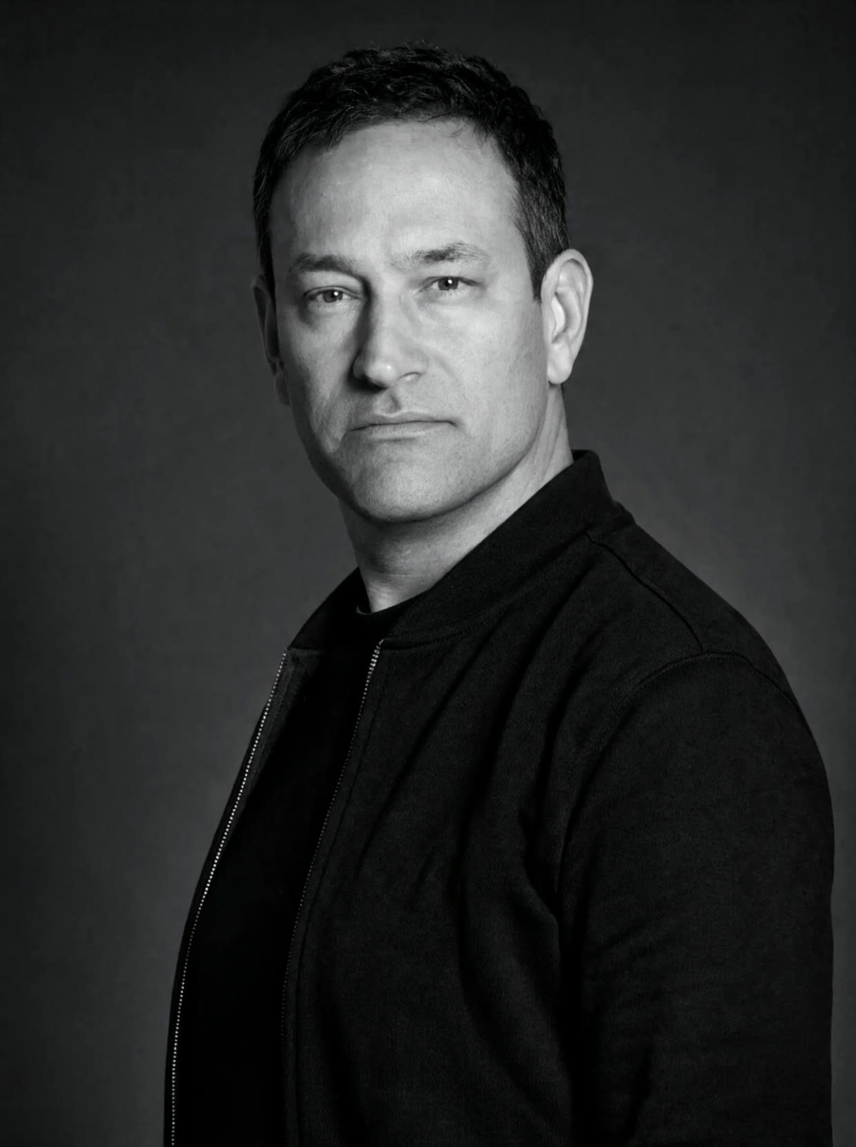 Çağdaş Agun, founder of Agun Security: black and white studio portrait in a black jacket