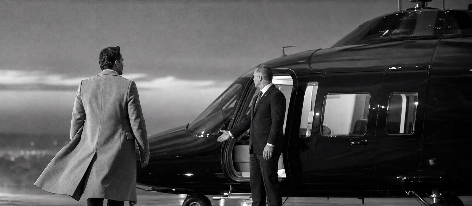 Passenger walking to a private helicopter as a protection officer shows the way to the cabin door